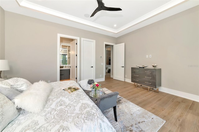 bedroom featuring baseboards, light wood-style floors, and a raised ceiling