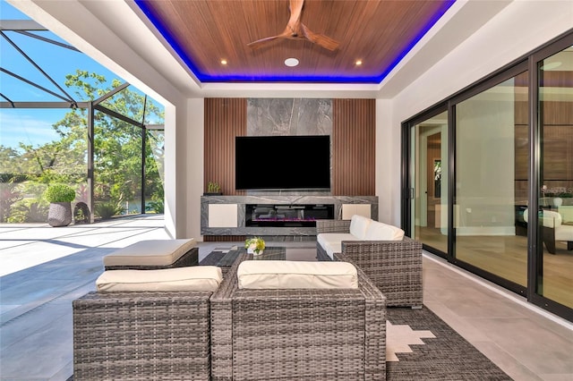 exterior space featuring an outdoor living space with a fireplace, a ceiling fan, and glass enclosure