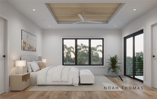 bedroom with a tray ceiling, access to exterior, and light wood-style floors