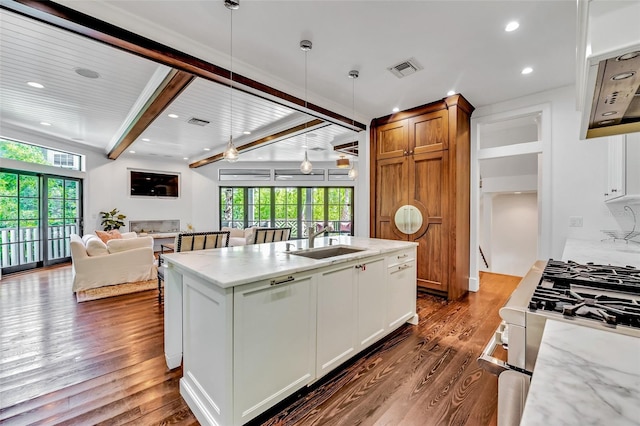 103 Park Ave, Anna Maria, FL 34216 - kitchen with dark wood finished floors, light stone counters, a sink, beamed ceiling, and open floor plan