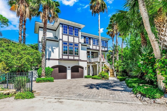 103 Park Ave, Anna Maria, FL 34216 - view of front of house with fence, an attached garage, stairs, stucco siding, and decorative driveway