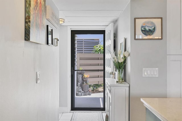 doorway to outside with tile patterned floors and baseboards