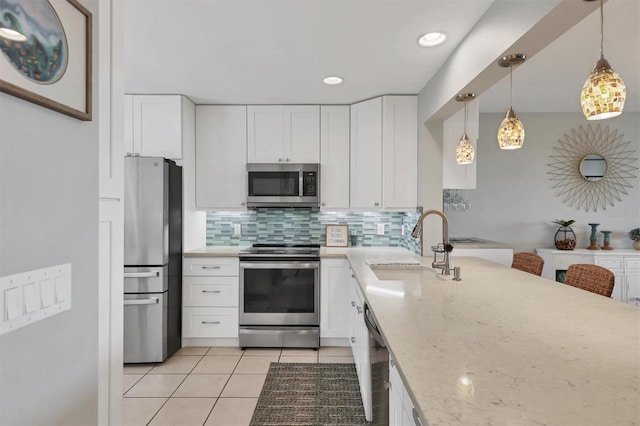 kitchen featuring light tile patterned floors, a sink, tasteful backsplash, appliances with stainless steel finishes, and white cabinetry