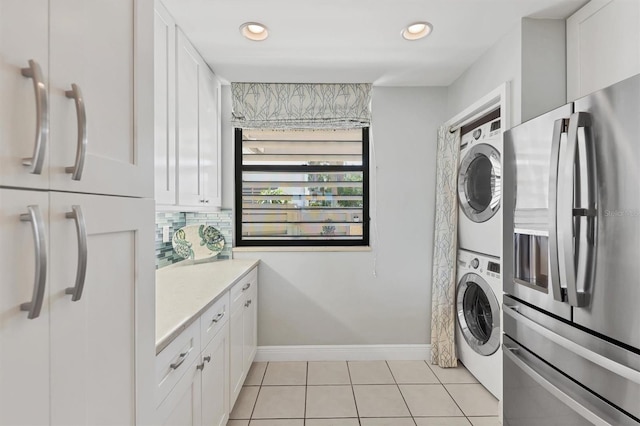 washroom featuring recessed lighting, stacked washer / dryer, laundry area, light tile patterned flooring, and baseboards