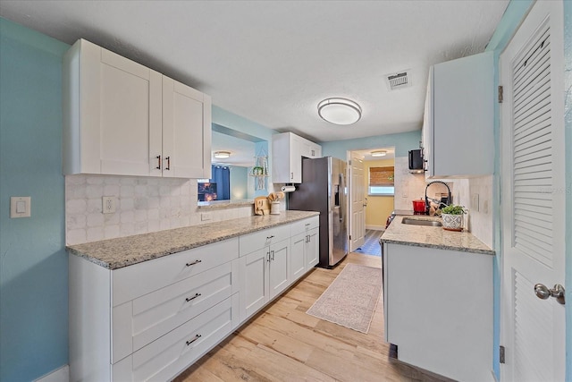 130 E Seminole Dr, Venice, FL 34293 - kitchen featuring stainless steel fridge, visible vents, decorative backsplash, light wood finished floors, and a sink