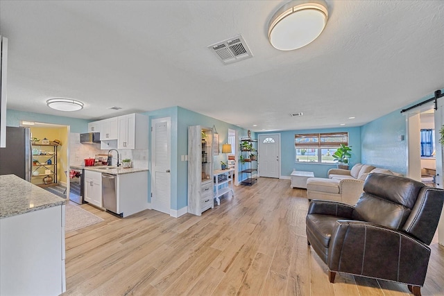 130 E Seminole Dr, Venice, FL 34293 - living room featuring light wood finished floors, baseboards, visible vents, and a barn door