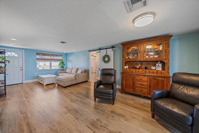 130 E Seminole Dr, Venice, FL 34293 - living room featuring visible vents, baseboards, light wood finished floors, and a barn door