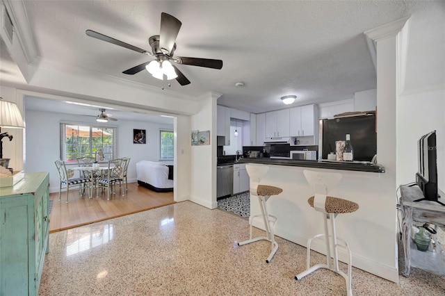 2307 Valencia Dr, Sarasota, FL 34239 - kitchen featuring light speckled floor, freestanding refrigerator, a kitchen bar, ceiling fan, and dishwasher