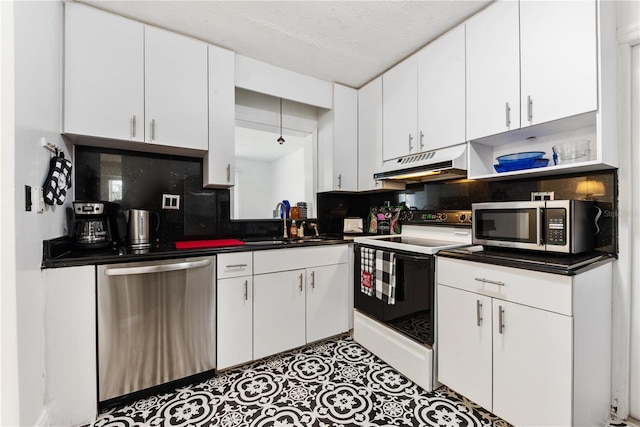 2307 Valencia Dr, Sarasota, FL 34239 - kitchen with under cabinet range hood, white cabinets, appliances with stainless steel finishes, and dark countertops