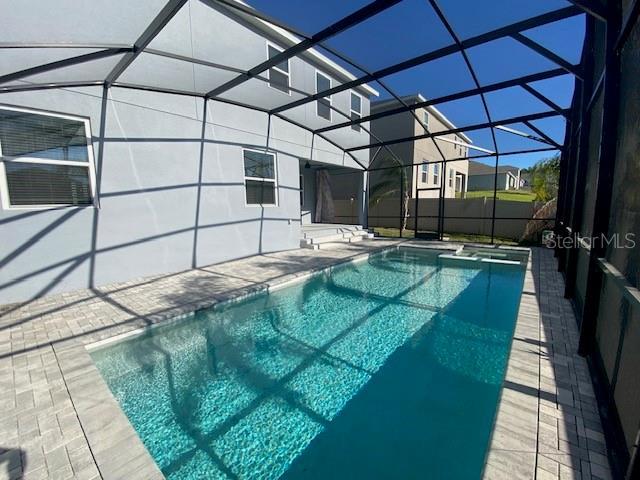 1142 Blarney St, Minneola, FL 34715 - view of pool featuring a patio, a pool with connected hot tub, and glass enclosure