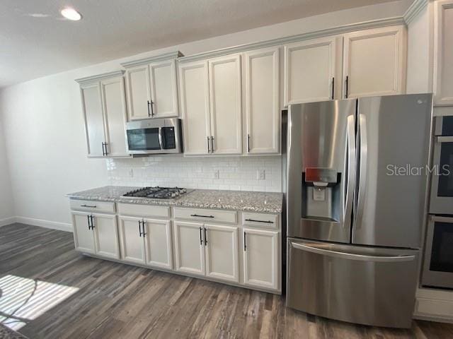 1142 Blarney St, Minneola, FL 34715 - kitchen featuring baseboards, light stone counters, backsplash, dark wood finished floors, and stainless steel appliances