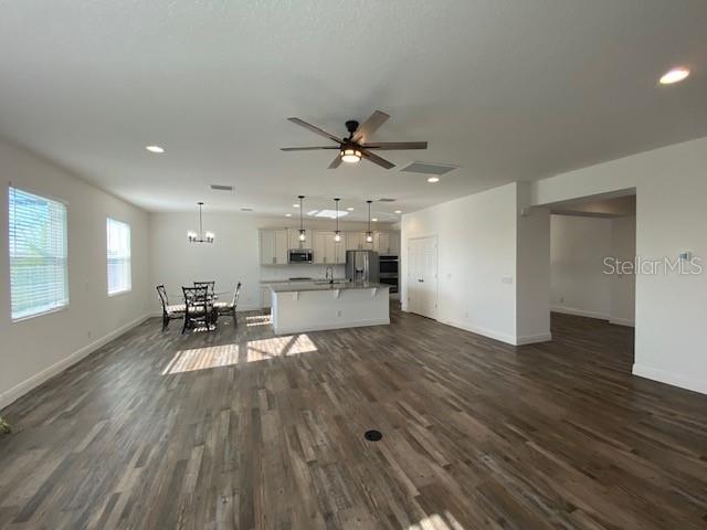 1142 Blarney St, Minneola, FL 34715 - living room with recessed lighting, dark wood-style floors, ceiling fan with notable chandelier, and baseboards
