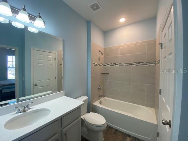 1142 Blarney St, Minneola, FL 34715 - bathroom featuring vanity, toilet, visible vents, bathtub / shower combination, and wood finished floors