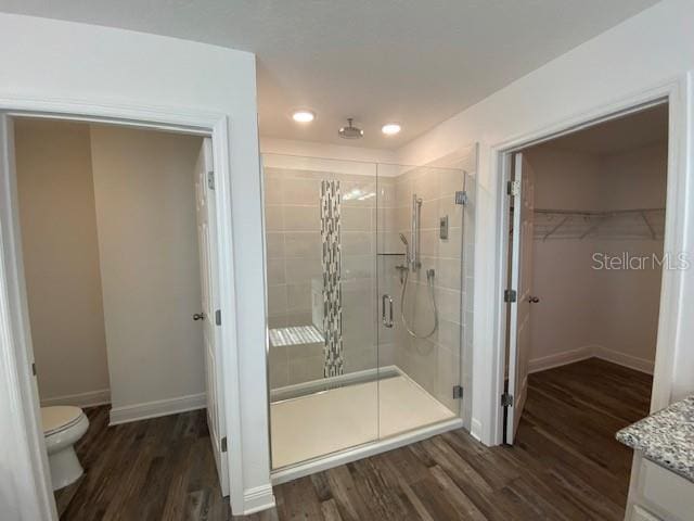 1142 Blarney St, Minneola, FL 34715 - bathroom with a shower stall, a walk in closet, baseboards, and wood finished floors
