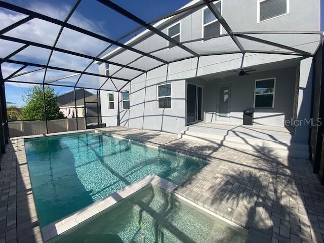 1142 Blarney St, Minneola, FL 34715 - view of swimming pool featuring a patio area, a pool with connected hot tub, glass enclosure, and ceiling fan