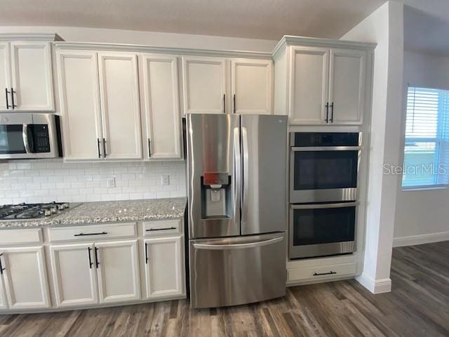 1142 Blarney St, Minneola, FL 34715 - kitchen with baseboards, light stone counters, backsplash, appliances with stainless steel finishes, and wood finished floors