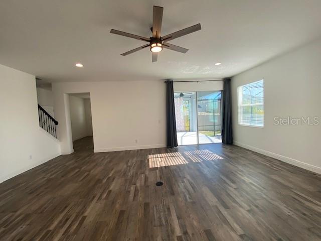1142 Blarney St, Minneola, FL 34715 - unfurnished living room with dark wood finished floors, baseboards, recessed lighting, a ceiling fan, and stairway