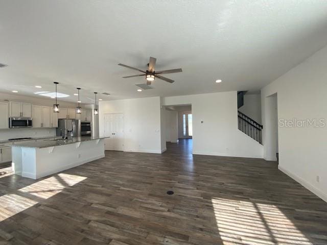 1142 Blarney St, Minneola, FL 34715 - unfurnished living room featuring dark wood-type flooring, ceiling fan, stairway, and recessed lighting