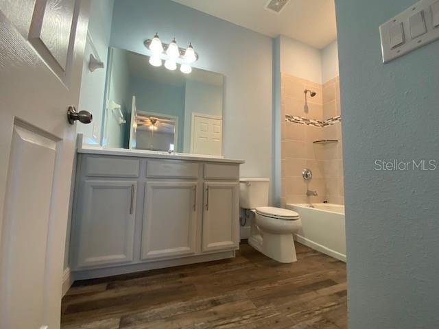 1142 Blarney St, Minneola, FL 34715 - bathroom featuring visible vents, toilet, shower / bath combination, wood finished floors, and vanity