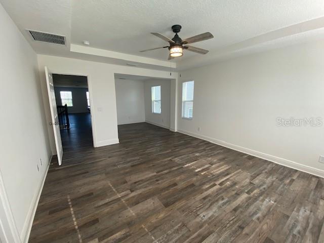 1142 Blarney St, Minneola, FL 34715 - unfurnished room with dark wood-type flooring, visible vents, a ceiling fan, and plenty of natural light