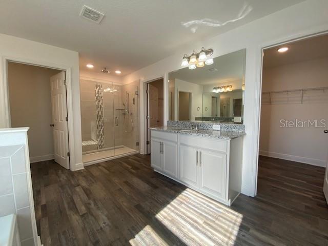 1142 Blarney St, Minneola, FL 34715 - bathroom with visible vents, baseboards, vanity, wood finished floors, and a stall shower