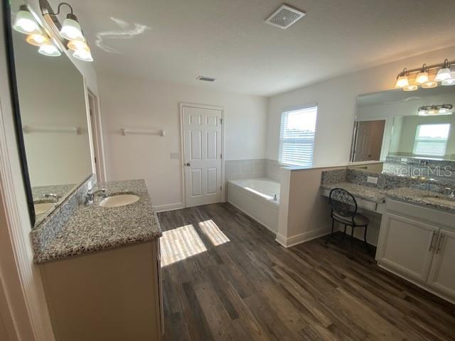 1142 Blarney St, Minneola, FL 34715 - bathroom with two vanities, a bath, a sink, and wood finished floors