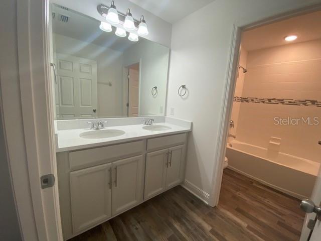 1142 Blarney St, Minneola, FL 34715 - bathroom with a sink, washtub / shower combination, double vanity, and wood finished floors