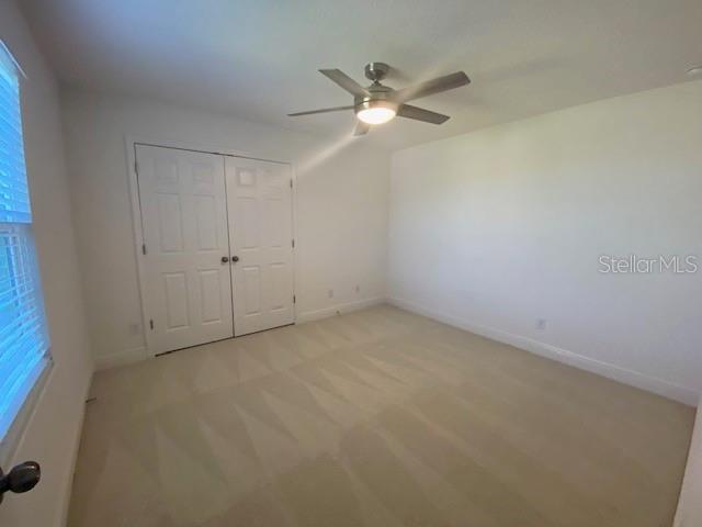 1142 Blarney St, Minneola, FL 34715 - unfurnished bedroom featuring a closet, baseboards, ceiling fan, and light colored carpet