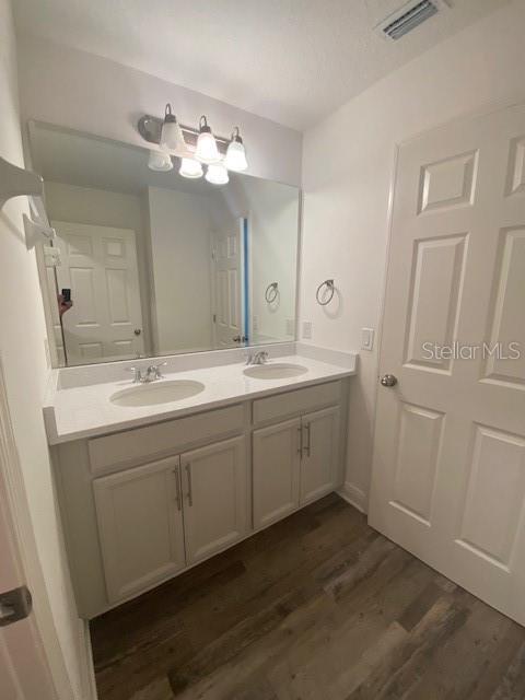 1142 Blarney St, Minneola, FL 34715 - bathroom featuring wood finished floors, double vanity, a sink, and visible vents