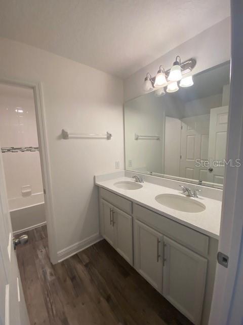 1142 Blarney St, Minneola, FL 34715 - bathroom with double vanity, baseboards, a sink, and wood finished floors