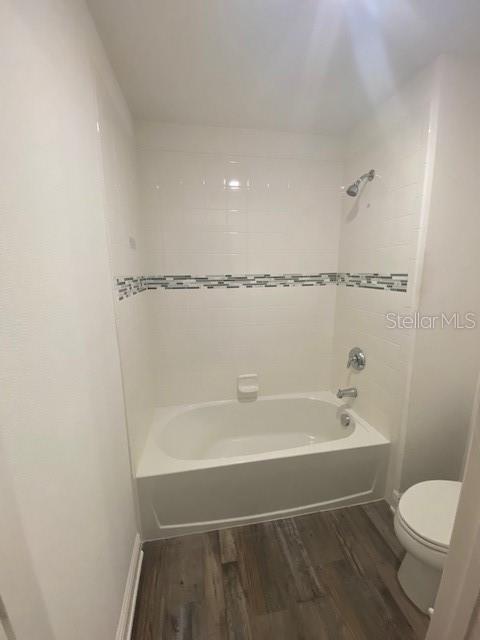 1142 Blarney St, Minneola, FL 34715 - full bathroom featuring toilet, shower / bath combination, wood finished floors, and baseboards