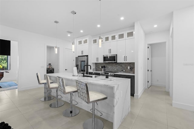 3724 SW 3rd St, Cape Coral, FL 33991 - kitchen featuring tasteful backsplash, white cabinets, a sink, appliances with stainless steel finishes, and a kitchen bar