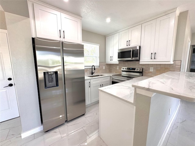 1142 Newhope Rd, Spring Hill, FL 34606 - kitchen with marble finish floor, a sink, a peninsula, appliances with stainless steel finishes, and white cabinetry