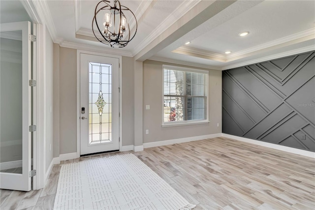 entrance foyer featuring ornamental molding, an inviting chandelier, and a raised ceiling