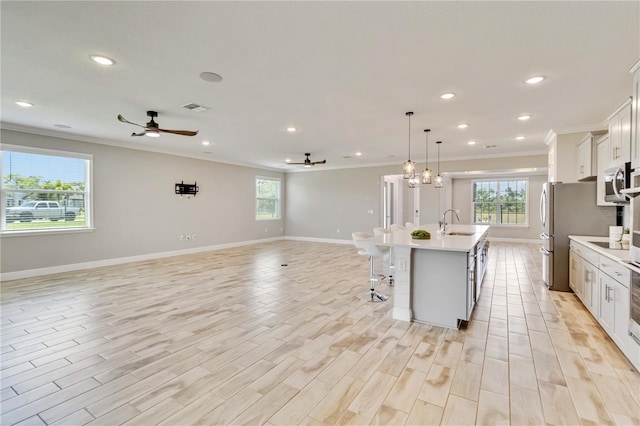 kitchen with open floor plan, visible vents, a ceiling fan, and ornamental molding