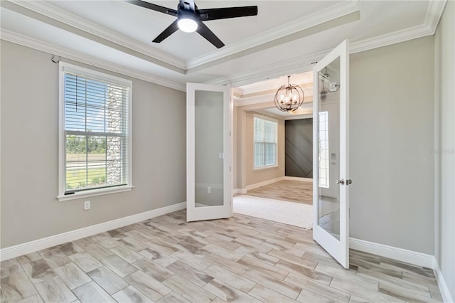 unfurnished room featuring french doors, a tray ceiling, ornamental molding, and baseboards