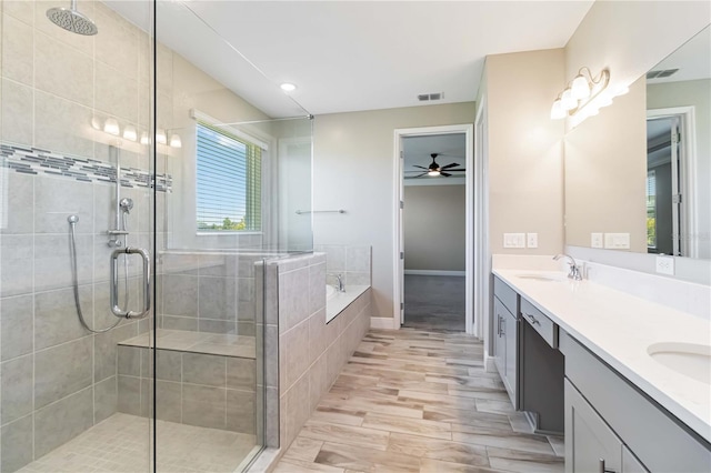 full bath with a stall shower, double vanity, a sink, and ceiling fan