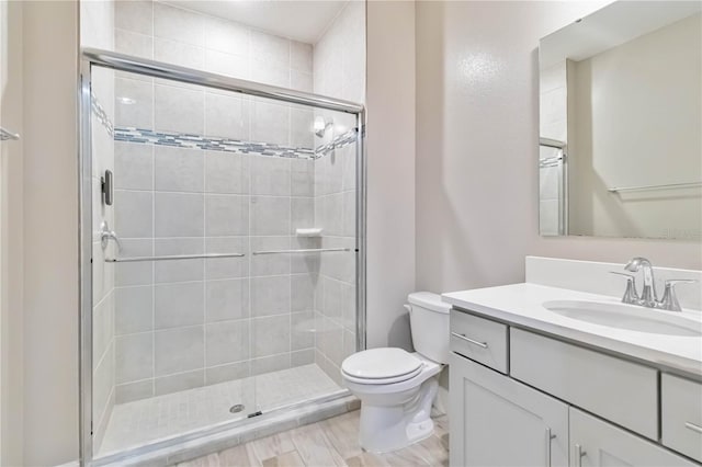 bathroom with toilet, a stall shower, and vanity
