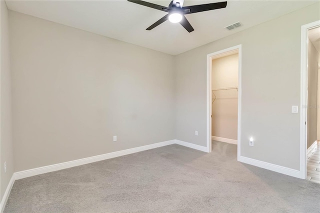 unfurnished bedroom featuring carpet, visible vents, a spacious closet, and baseboards