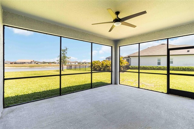 unfurnished sunroom with a ceiling fan, a water view, and a residential view