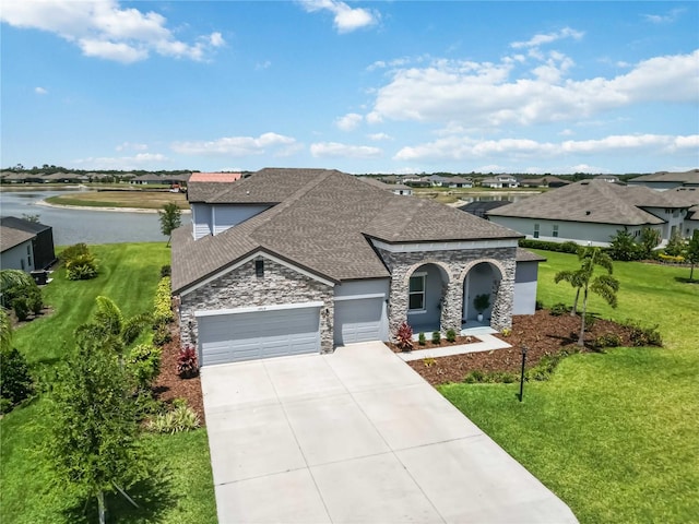 view of front of house with a front lawn, a shingled roof, driveway, stone siding, and an attached garage