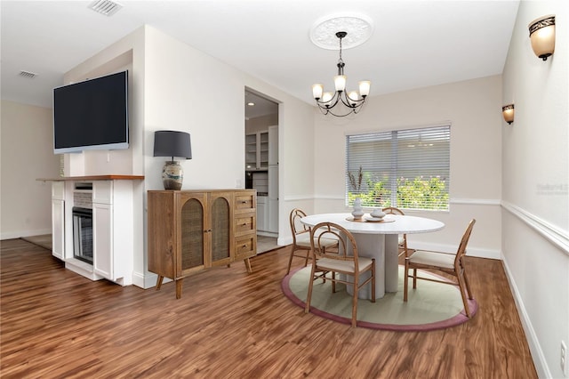 dining space featuring baseboards, a notable chandelier, wood finished floors, and visible vents