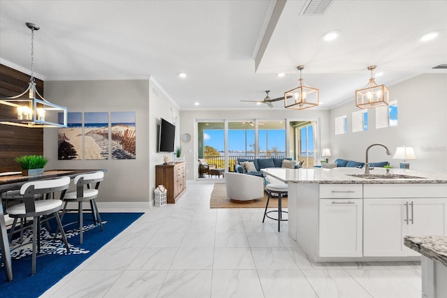 kitchen with a sink, open floor plan, crown molding, marble finish floor, and recessed lighting