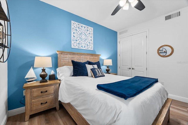 bedroom featuring baseboards, a closet, visible vents, and wood finished floors