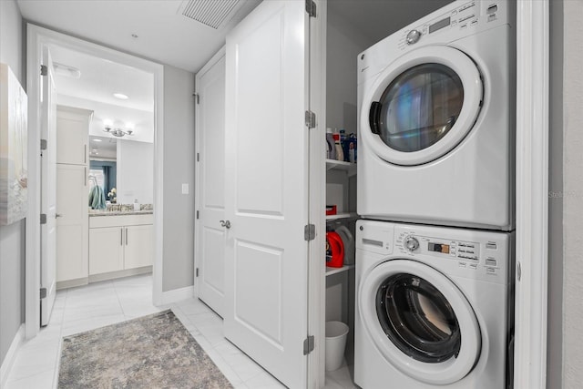 laundry room with marble finish floor, laundry area, visible vents, stacked washing maching and dryer, and baseboards