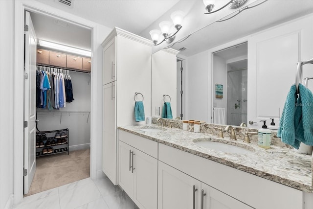 bathroom featuring a stall shower, double vanity, a sink, and a walk in closet