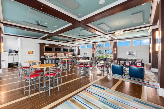 dining space featuring coffered ceiling, beam ceiling, wood finished floors, and a ceiling fan