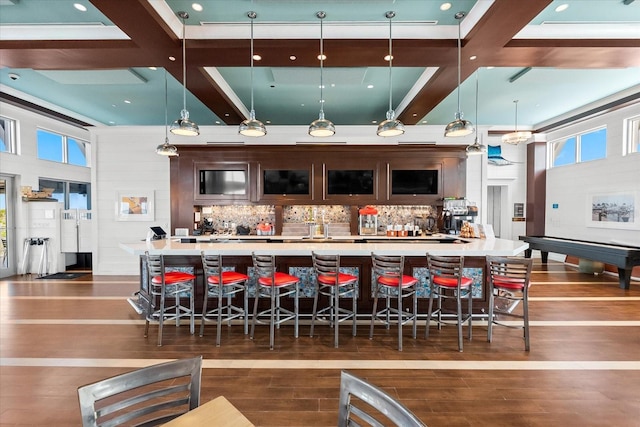 bar featuring tasteful backsplash, dark wood-style flooring, coffered ceiling, a bar, and hanging light fixtures
