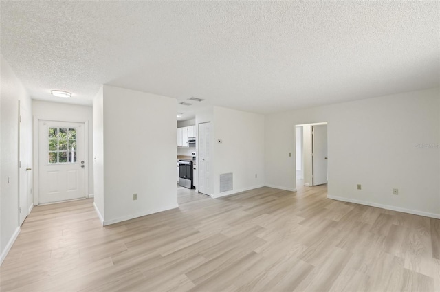 unfurnished living room featuring a textured ceiling, visible vents, baseboards, and light wood-style floors