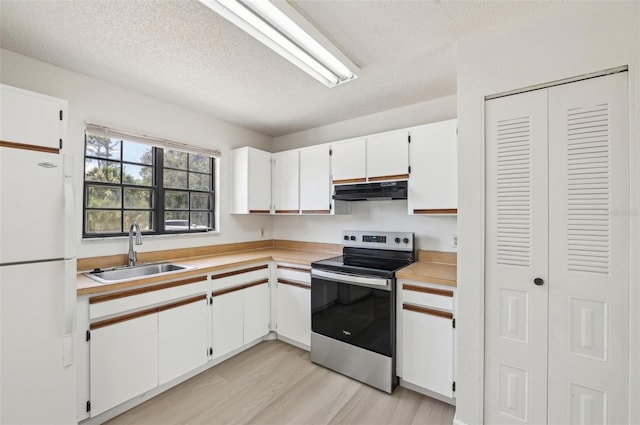 kitchen with freestanding refrigerator, light countertops, a sink, and stainless steel range with electric stovetop